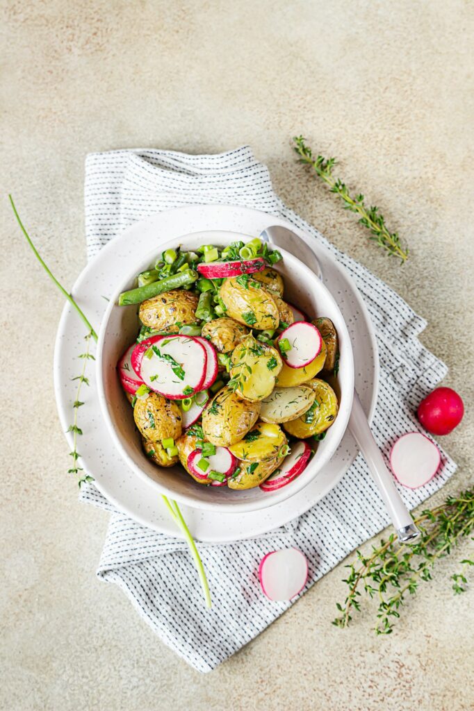 Tasty hot potato salad with green beans, fresh radishes and herbs.